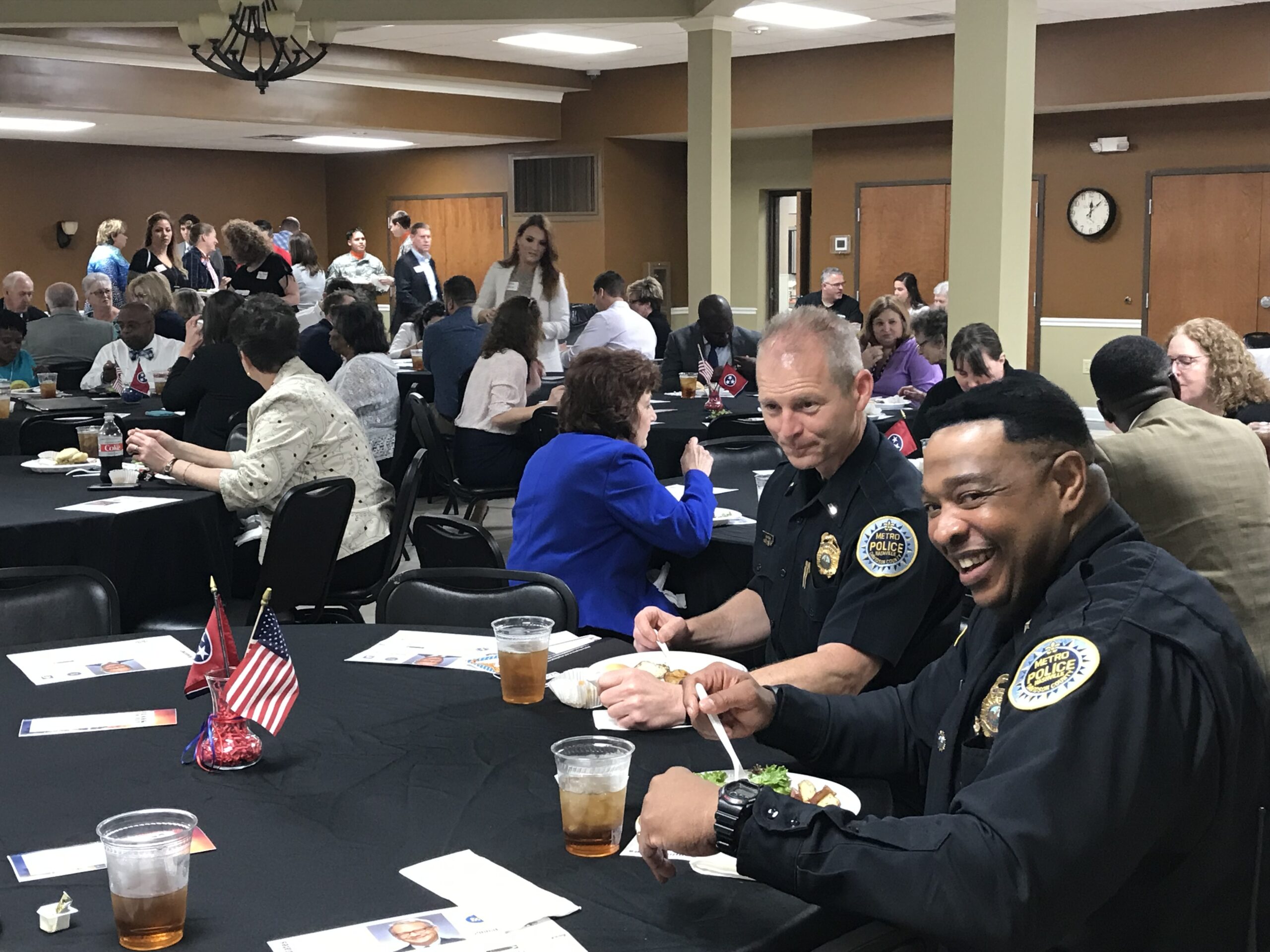 Several groupd sit at tables for the luncheon, including two members of local police enjoying a meal.